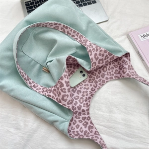 Detail view of large mint green suede tote bag with pink leopard print lining and inner pocket