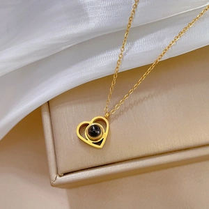 Macro shot of a gold heart pendant necklace featuring a black center stone on silk