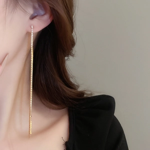 Detail of long gold tassel earrings with rhinestones shown on model side profile