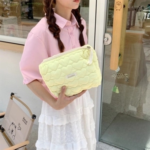 Detail of light yellow quilted heart pattern cosmetic bag with Sezakka woven label