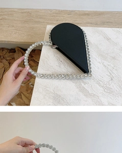 Detail of a heart-shaped evening clutch featuring black satin and sparkling rhinestones