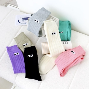 Macro detail of colorful ribbed knit socks featuring unique cartoon eye embroidery