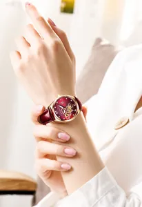 Vista dettagliata di un elegante orologio da donna in oro rosa con cinturino in pelle bordeaux.