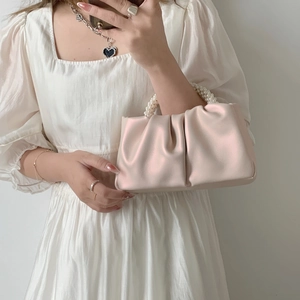Close-up of pink ruched cloud bag featuring elegant pearl bead handle and satin texture