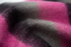 Close-up of thick striped knit scarf showing soft pink, grey, and black wool texture