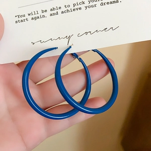 Macro detail of large matte Klein blue round hoop earrings with a smooth painted finish