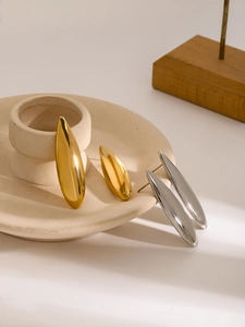 Close-up of minimalist teardrop earrings in gold and silver finish on a ceramic plate