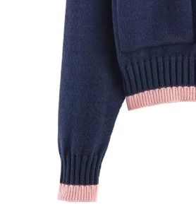 Détail d'un pull en maille bleu marine avec poignets et ourlet côtelés roses et texture