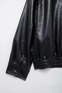 Detail of elastic hem and button cuff on a black faux leather bomber jacket