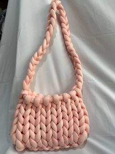 Close-up of pink handmade chunky knit bag featuring soft texture and woven strap