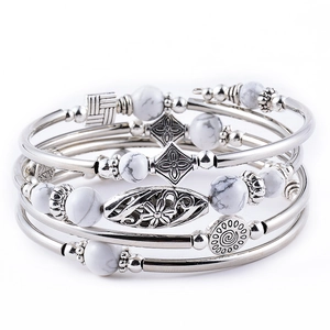 Detail of multi-layer bracelet with silver metal charms and white marble beads