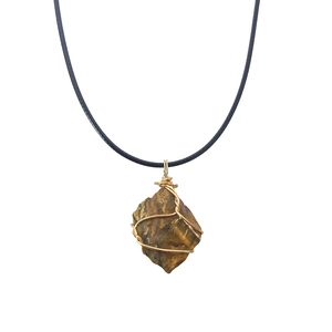 Detailed macro view of raw tiger eye stone pendant wrapped in handmade golden wire