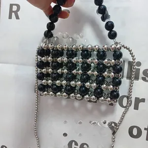 Detail of handmade beaded mini bag featuring black and silver beads with woven texture