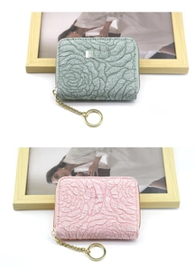 Close-up of sage green and pink mini wallets with embossed floral textures and gold zippers
