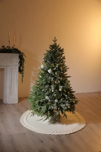 Detail of white knitted Christmas tree skirt with cable knit pattern and cozy texture