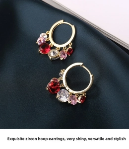 Detail of gold hoop earrings with multi-colored cubic zirconia charms on green silk