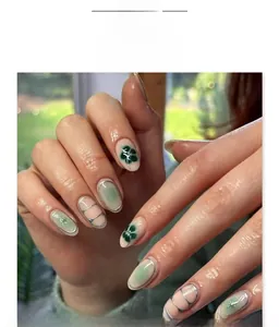 Detailed view of almond-shaped press-on nails with green clover motifs and shimmer finish