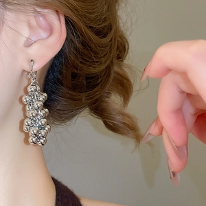 Boucles d'oreilles argentées avec pampilles géométriques portées par un mannequin