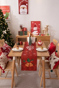 Detailed view of red plaid Christmas table runner with Santa Claus and festive snowflake patterns