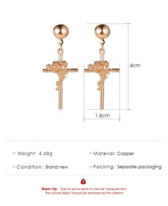 Détail des boucles d'oreilles croix en or rose avec rose en relief, hauteur 4cm et 4,48g