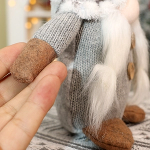 Detail of Christmas gnome with knitted texture, wooden button, and faux fur beard