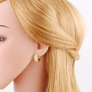 Elegant gold U-shaped huggie earrings with cubic zirconia pavé stones on a model