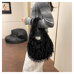 Detail of a chic black fuzzy shoulder bag with long tassel fur texture for women
