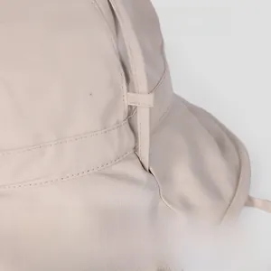 Detail shot of a beige dome sun hat featuring a minimalist silk-like fabric and side ribbon