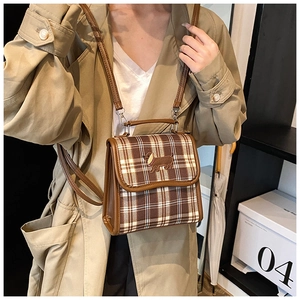 Detail of vintage brown plaid bag with dog embroidery on flap shown by model