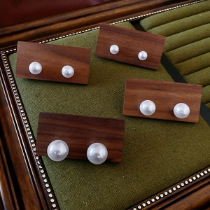 Detail view of four pairs of graduated pearl earrings on dark wooden display cards