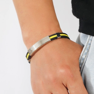 Gros plan d'un bracelet pour homme en silicone noir et jaune avec plaque en métal argenté
