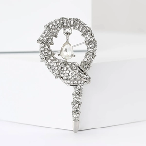 Detailed close-up of a silver snake brooch with sparkling rhinestones and a pear-cut drop