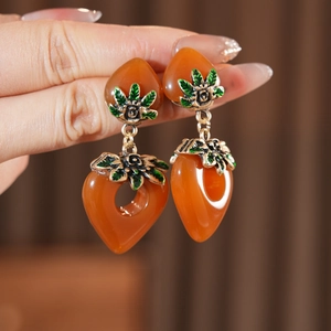 Makroaufnahme von Vintage-Herzohrringen mit orangefarbenem Harz und grünen Emaille-Details