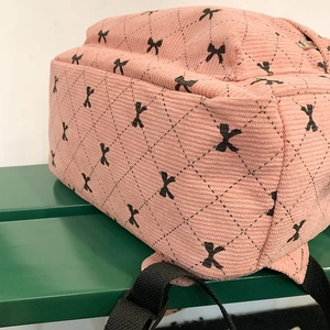 Detail of pink corduroy school bag showing diamond quilting and black bow patterns
