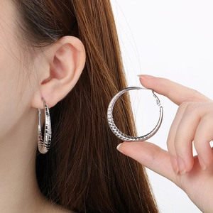 Detailed view of large silver hoop earrings with horizontal stripes on model