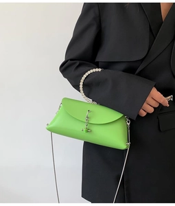 Detail of green crossbody bag with rhinestone handle and silver clasp on black blazer