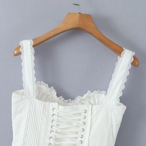 Detail of white corset top with lace trim, thin straps and lace-up back design