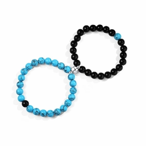 Detail of magnetic heart clasp connecting blue marble and black matte stone bead bracelets