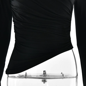 Detailed close-up of the gathered pleats and irregular hemline on a black long sleeve top