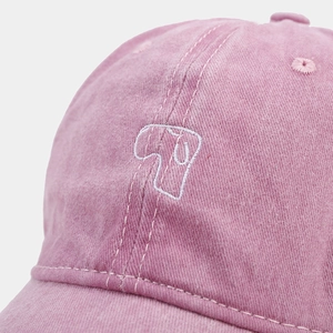Detailed close-up of pink washed cotton baseball cap with white abstract embroidery stitch