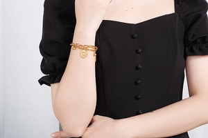 Detail of double-layer stainless steel bracelet featuring sun medallion and gold beads