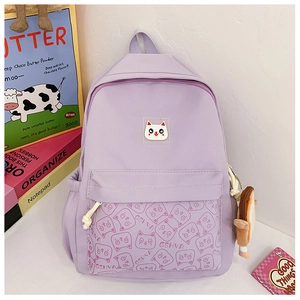 Detail of purple school backpack showing cat embroidery and plush pendant charm