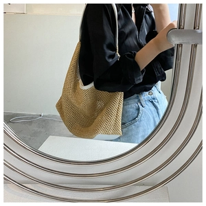 Chic khaki hollow woven straw bag with white strap shown in a creative mirror reflection