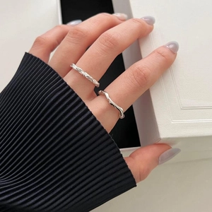 Close-up of minimalist 925 sterling silver braided and wavy open rings on finger