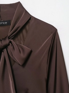 Dettaglio dello scollo dell'abito a foulard in raso di seta con fiocco marrone cioccolato