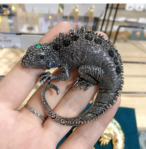 Close-up of vintage lizard brooch with brown gemstones and green zircon eyes details