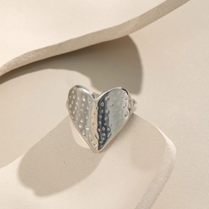 Bague cœur argentée avec finition texturée et polie sur un socle élégant