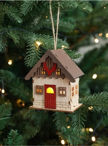 Close-up of LED wooden Christmas house ornament with reindeer decor hanging on a tree