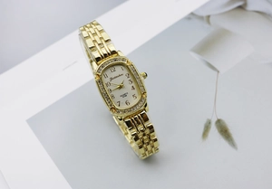 Detailed side view of a gold-toned quartz watch with rhinestone bezel and five-link strap