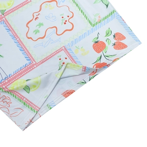 Detailed view of summer dress hem with strawberry and lemon print on polyester fabric